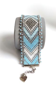 a beaded bracelet with a heart charm hanging from it's side on a white surface