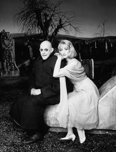 an old black and white photo of two people sitting on a bench in front of a cemetery