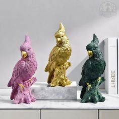 three different colored owl figurines sitting next to each other on a white surface