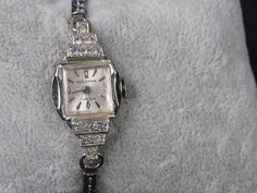 "For your consideration is this elegant vintage 1950's silver tone Woldman watch. It has a feminine decorative band, a beautiful face and decorative rhinestones accents. This watch has been professionally cleaned and repaired. It is a wind-up watch so I have the stem pulled out so it doesn't run down. It is in excellent condition. It band measures 5 1/2\" but it does stretch. The face measures 1/2\" across. Beautiful gift for any occasion.  I do not clean watches or jewelry. Thank you for visiti Art Deco Silver Diamond Watch For Weddings, Silver Art Deco Watches For Weddings, Silver Art Deco Diamond Watch For Wedding, Art Deco Silver Wedding Watches, Vintage Watches With Diamond Accents As Gift, Silver Art Deco Diamond Watch For Evening, Silver Art Deco Diamond Evening Watch, Formal White Gold Watches With Rhinestones, Silver Vintage Diamond Watch For Formal Occasions