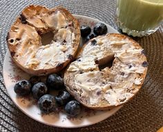 two pieces of bread on a plate with blueberries next to a glass of green juice