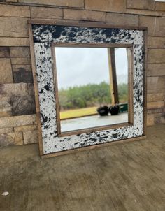 a mirror sitting on top of a wooden floor next to a brick wall and window