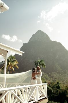 a bride and groom standing on a balcony looking at the mountains in st thomas, virgin islands