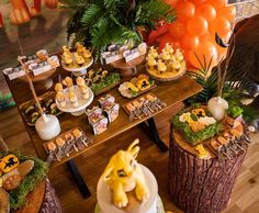 a table topped with lots of desserts and orange balloons