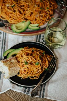 two plates of spaghetti and cucumbers on a table