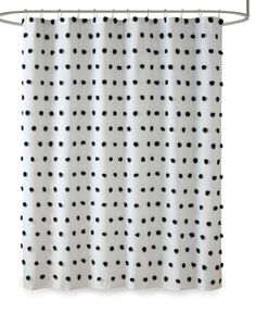 black and white shower curtain with polka dot pattern on the bottom, hanging from a metal rod