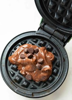 a waffle topped with chocolate chips on top of a white table next to a green container