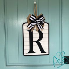 a door hanger with the letter r on it and a bow hanging from it