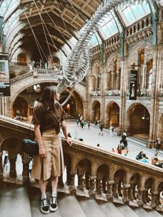 a woman standing on top of a set of stairs next to a giant fish skeleton