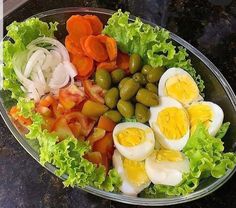 a salad with hard boiled eggs, tomatoes, lettuce and olives in it