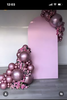 an artistic display with balloons and flowers on the floor in front of a pink wall