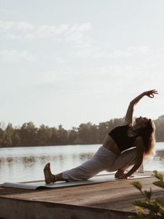 a woman is doing yoga on the dock