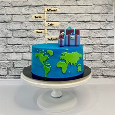 a blue and green cake sitting on top of a white table next to a brick wall