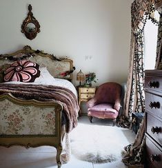 a bed room with a neatly made bed next to a dresser and mirror on the wall