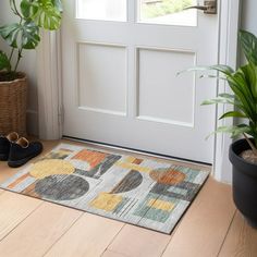 a pair of black slippers sitting on top of a door mat next to a potted plant