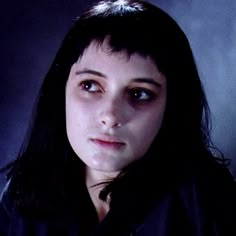 a woman with black hair and blue eyes staring at the camera