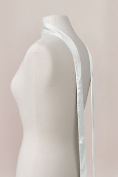 a white mannequin with a bow on it's head and neckline