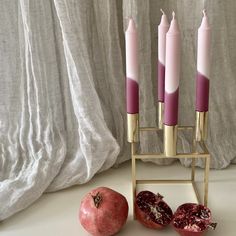 three candles and two pomegranates on a stand