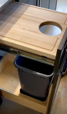 a kitchen counter with a trash can under the sink and an open drawer underneath it