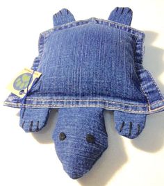 a blue stuffed animal laying on top of a denim pillow that has been made to look like a turtle