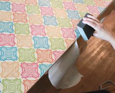 someone is using a piece of paper to cut out the pattern on this tablecloth