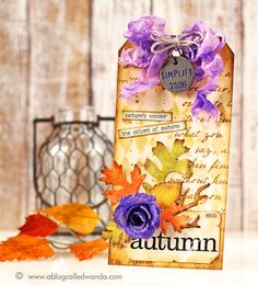 an autumn card with purple flowers and leaves on the table next to a candle holder