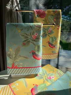 two towels are hanging on a clothes line in front of a window with trees and flowers