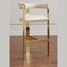 a white and gold bar stool in front of a wall with a wooden flooring