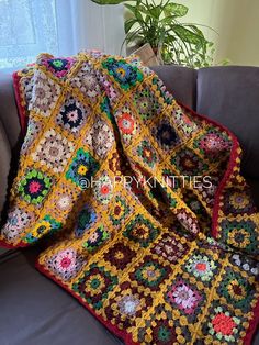 a crocheted granny blanket sitting on top of a couch next to a potted plant