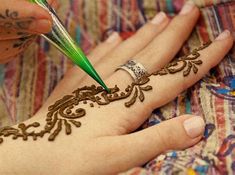 a woman with henna on her hand and a green pen in her other hand