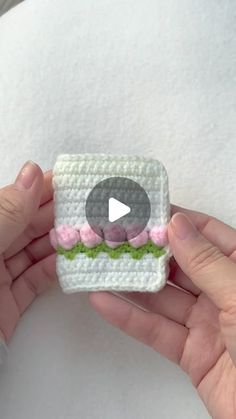 someone is holding a small crocheted toy with a video playing button on it