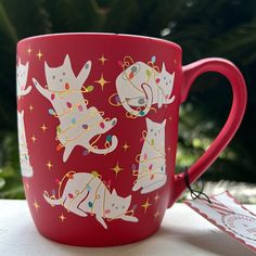 a red coffee cup with white cats on it