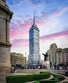 a very tall building towering over a city filled with lots of green grass and bushes