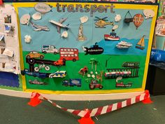 a bulletin board with cars, trucks and planes on it in front of a traffic cone