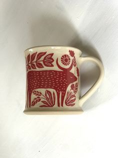 a red and white cup with an animal design on the side, sitting on a white surface