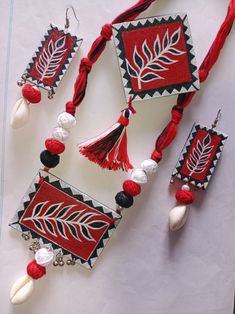 three pieces of red and white jewelry with tassels