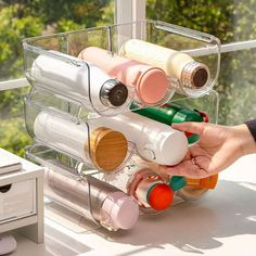 a person is holding an empty bottle in front of a rack with bottles on it