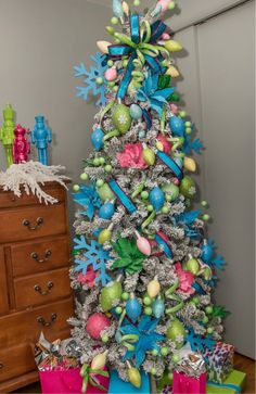 a decorated christmas tree with blue, green and pink ornaments on it's branches