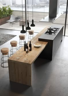 a modern kitchen with an island counter and stools in front of the stove top