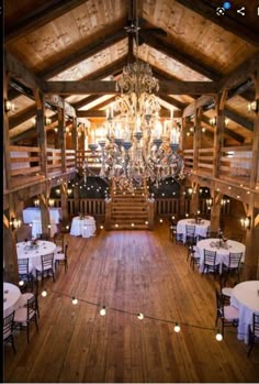 the inside of a rustic wedding venue with chandeliers and white tablecloths