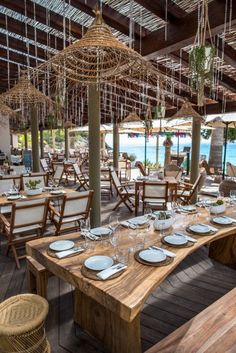 an outdoor dining area with wooden tables and chairs, white plates and silverware hanging from the ceiling