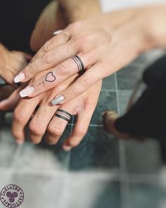 two people holding each other's hands with tattoos on their fingers and one has a heart tattoo