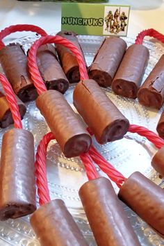 chocolate covered candy sticks are on a silver platter with red twine around them