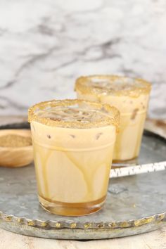 two glasses filled with liquid sitting on top of a metal tray