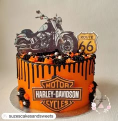 a motorcycle themed birthday cake with orange icing and black frosting on the top