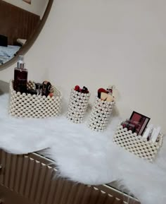 three containers with makeup on top of a white fur covered floor next to a mirror