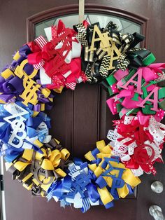 a colorful wreath is hanging on the front door with letters and bows attached to it