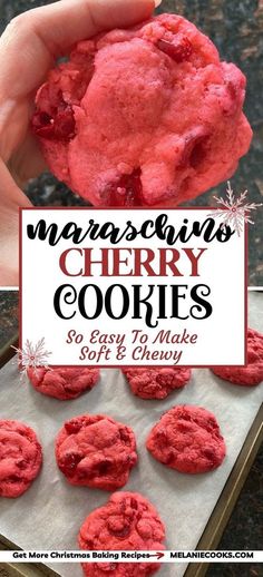 a hand holding up a red cookie in front of some cookies on a baking sheet