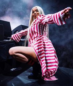 a woman dressed in red and white striped dress on stage with her arms spread out