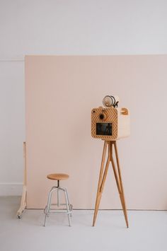 an old fashioned camera sitting on top of a wooden tripod next to a stool